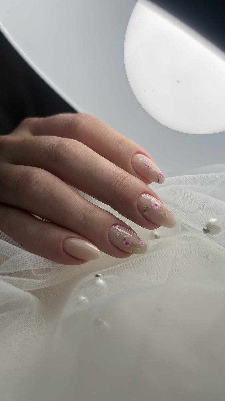 Nude almond nails with delicate hand-painted pink flowers on bridal tulle